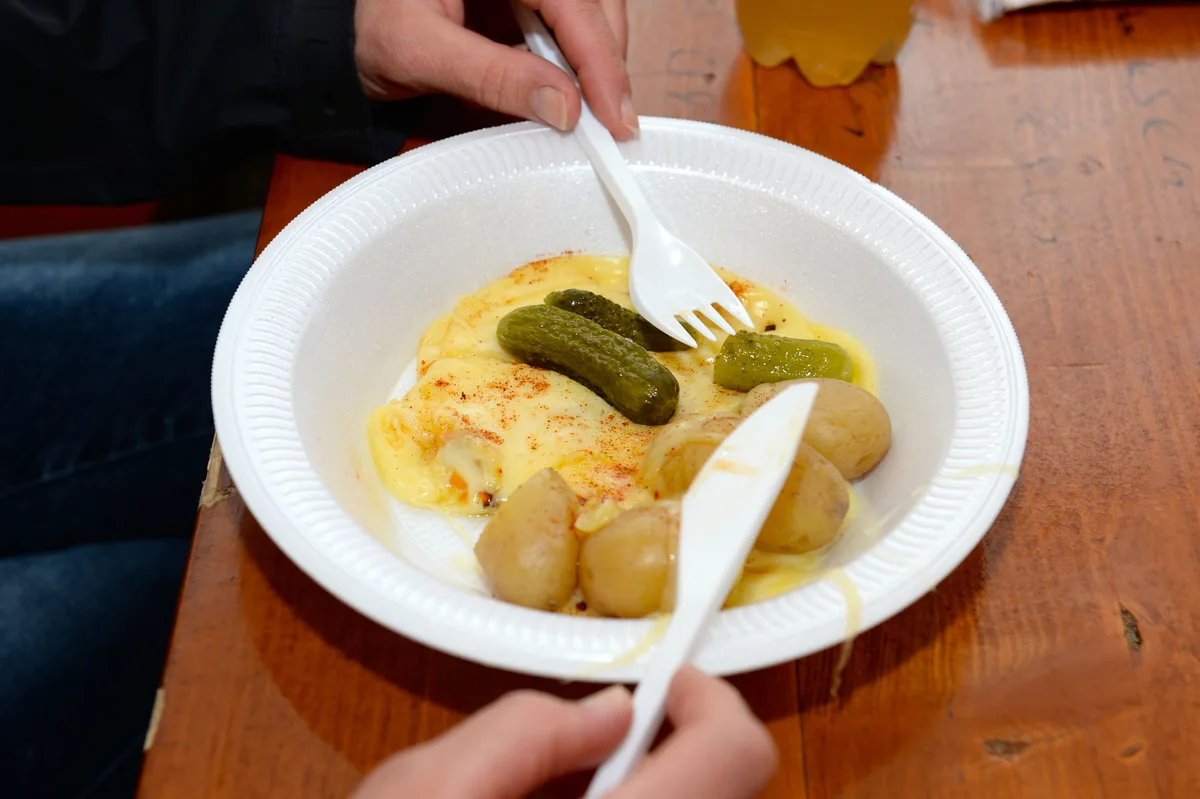 Ein Teller mit Raclette, Kartoffeln und Gürkchen.